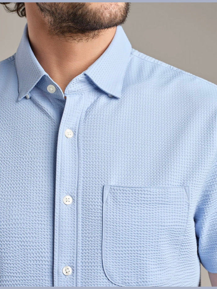 Close up of textured seersucker fabric and white buttons on shirt