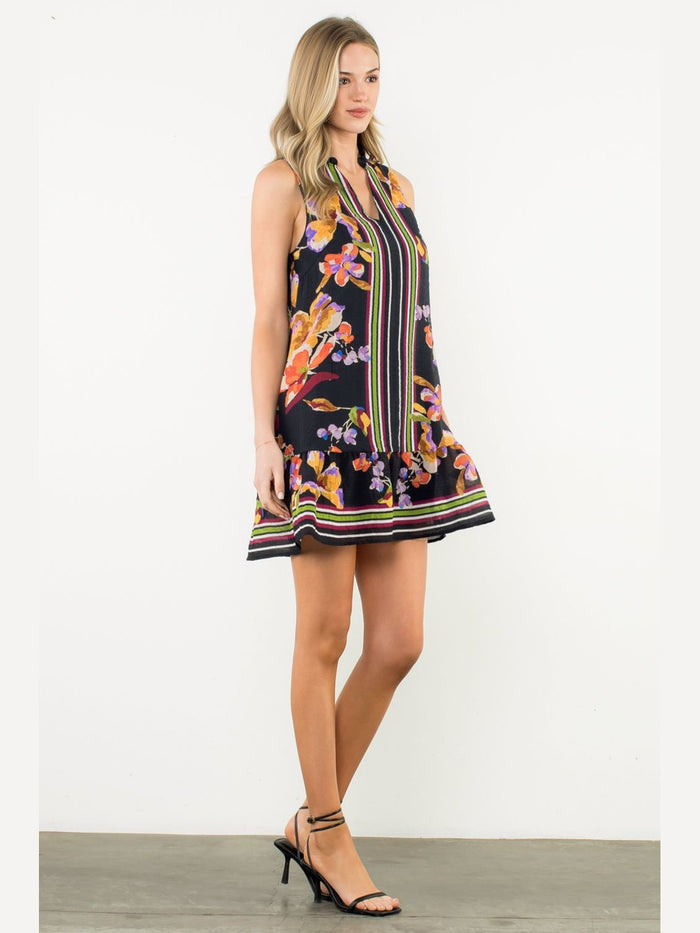 Black sleeveless floral mini dress with orange and purple flowers, green vertical stripes, and ruffled hem